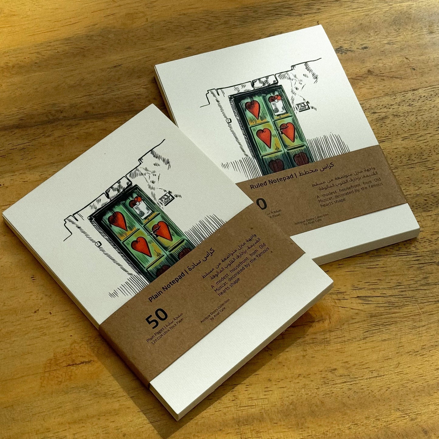 Two small books or notebooks with a design on the cover, placed on a wooden surface.
